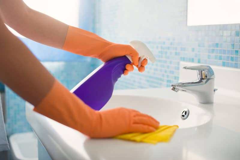 67 Side Hustle Ideas to Make an Extra $1,000 Per Month 5 woman cleaning bathroom at home, cleaning sink and faucet with spray detergent.